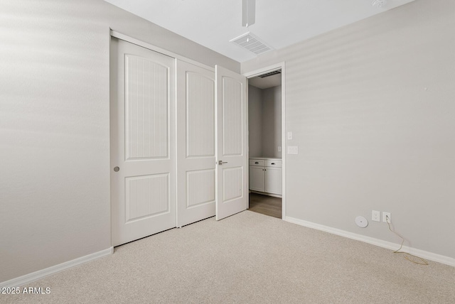 unfurnished bedroom with a closet, visible vents, baseboards, and carpet