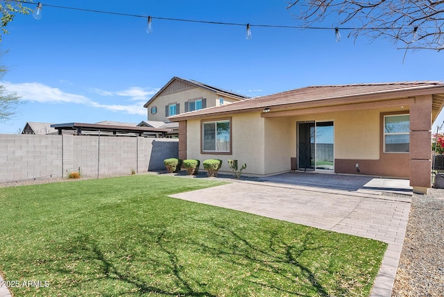 rear view of property featuring a yard, a patio area, fence, and stucco siding