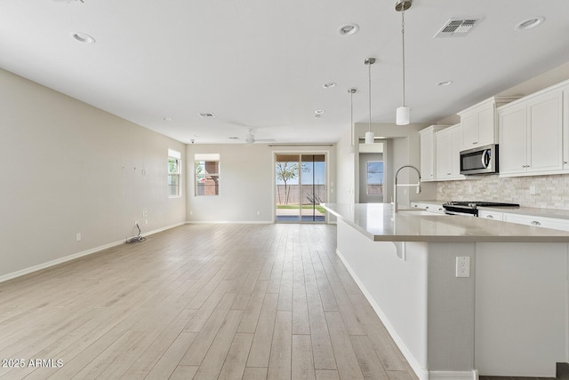 kitchen featuring visible vents, a sink, appliances with stainless steel finishes, tasteful backsplash, and open floor plan