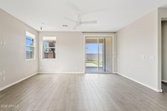 empty room featuring visible vents, ceiling fan, baseboards, and wood finished floors