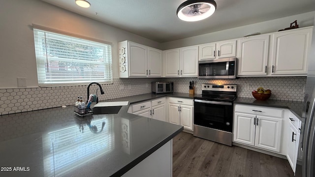 kitchen with white cabinetry, dark countertops, appliances with stainless steel finishes, and a sink