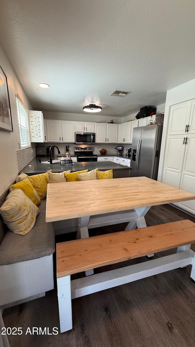 dining space with visible vents, a textured ceiling, and dark wood-style flooring