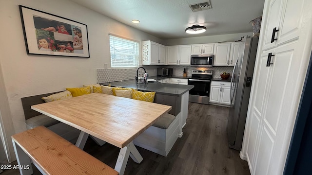 kitchen featuring visible vents, breakfast area, appliances with stainless steel finishes, white cabinetry, and a sink