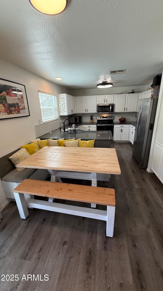 dining space with a textured ceiling, dark wood-type flooring, visible vents, and breakfast area