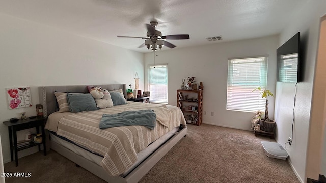 carpeted bedroom featuring a ceiling fan, visible vents, and baseboards