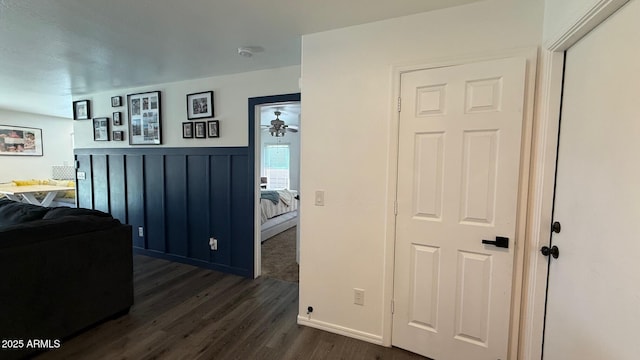 living area featuring dark wood finished floors, wainscoting, and ceiling fan