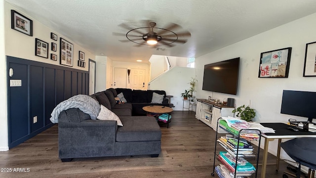 living area with dark wood-type flooring, a ceiling fan, visible vents, and a textured ceiling