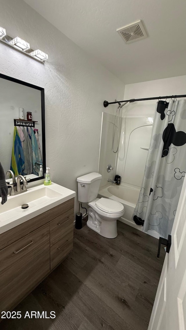 full bathroom with vanity, shower / bathtub combination with curtain, wood finished floors, visible vents, and toilet