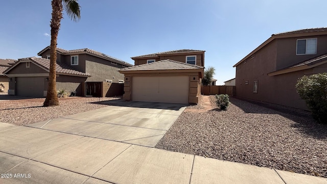 view of front facade with stucco siding, driveway, fence, an attached garage, and a tiled roof