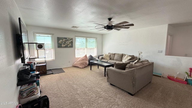 living room featuring ceiling fan, carpet, visible vents, and a textured ceiling