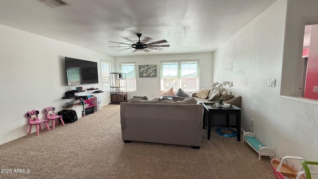 carpeted living room featuring visible vents, a textured ceiling, a ceiling fan, and a textured wall