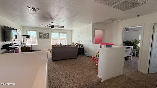 living area featuring a ceiling fan, visible vents, and carpet floors