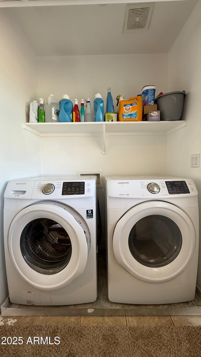 washroom with visible vents, washing machine and dryer, and laundry area