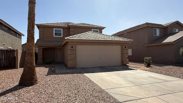 view of front of home with fence, driveway, stucco siding, a garage, and a tiled roof