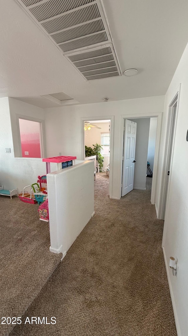 hall featuring visible vents, carpet, and baseboards