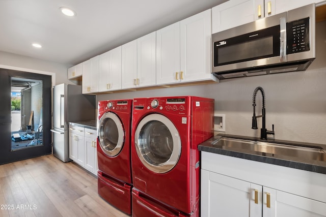 washroom with separate washer and dryer, sink, and light hardwood / wood-style flooring