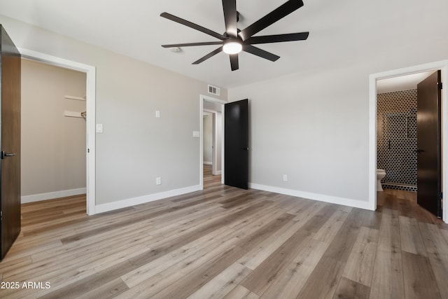 unfurnished bedroom featuring ensuite bath, ceiling fan, light hardwood / wood-style flooring, a spacious closet, and a closet