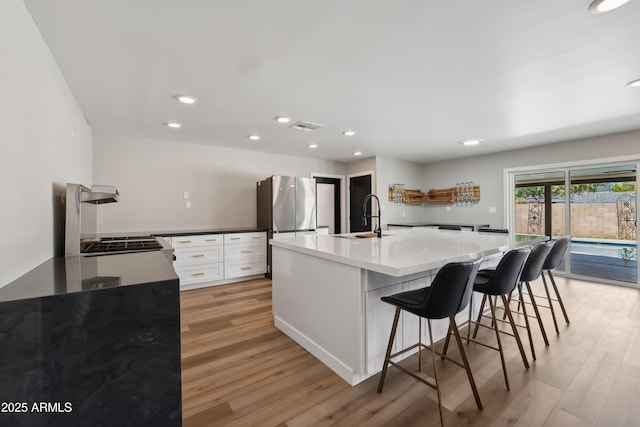 kitchen featuring white cabinets, a breakfast bar, sink, and light hardwood / wood-style flooring