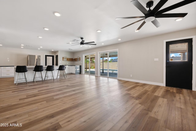 unfurnished living room with light wood-type flooring and ceiling fan