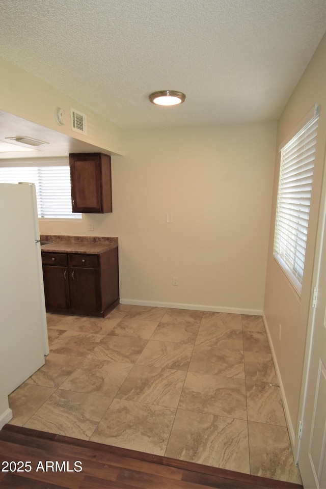 8124 N 33rd Dr, Phoenix, AZ 85051 - kitchen with freestanding refrigerator, dark brown cabinetry, a textured ceiling, visible vents, and baseboards