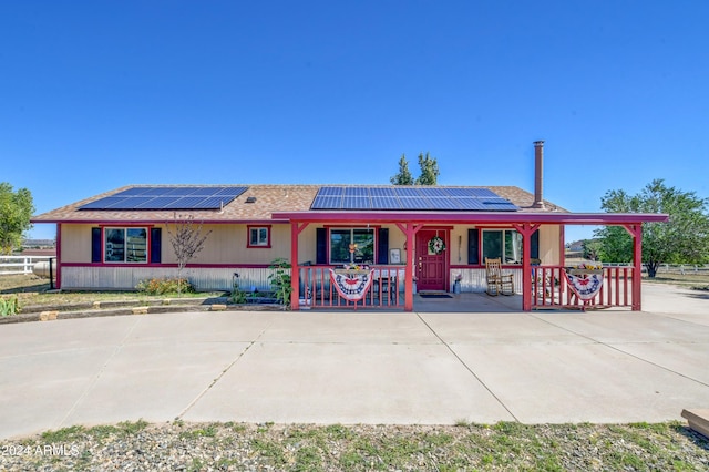 ranch-style house with solar panels and a porch