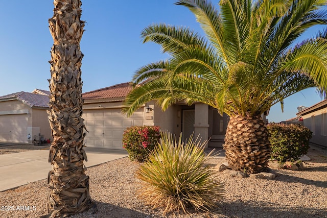 view of front of property featuring stucco siding, an attached garage, a tile roof, and driveway