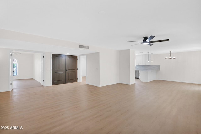 unfurnished living room with ceiling fan, a chandelier, light wood-type flooring, and baseboards