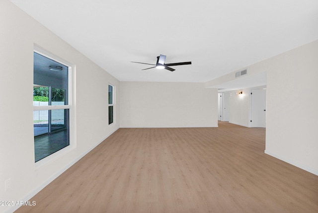spare room featuring light wood-type flooring, a ceiling fan, and baseboards