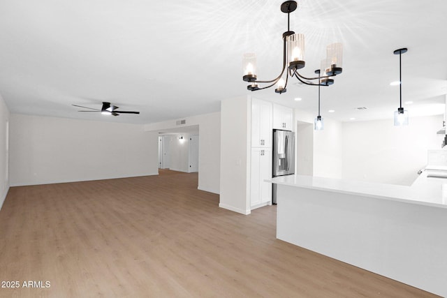 unfurnished living room featuring light wood-style floors, a chandelier, a ceiling fan, and recessed lighting