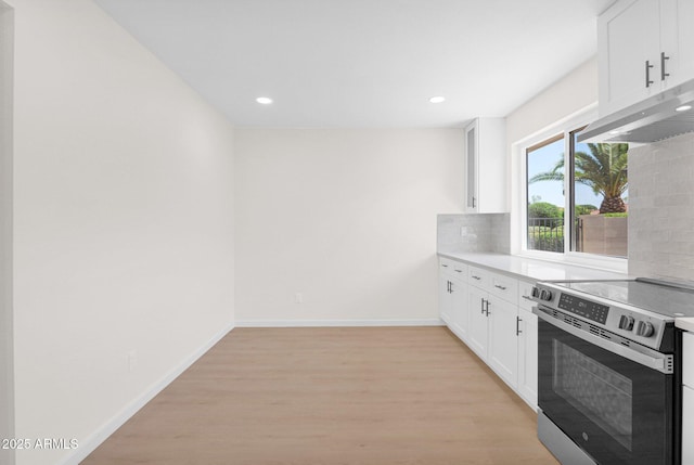 kitchen with electric stove, under cabinet range hood, light wood-type flooring, decorative backsplash, and white cabinetry