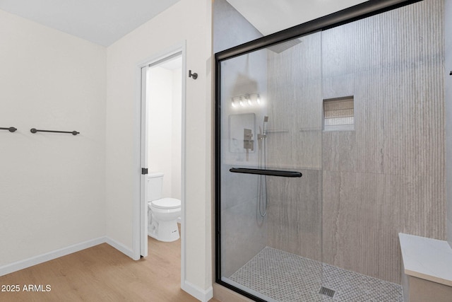 full bathroom with a shower stall, wood finished floors, toilet, and baseboards