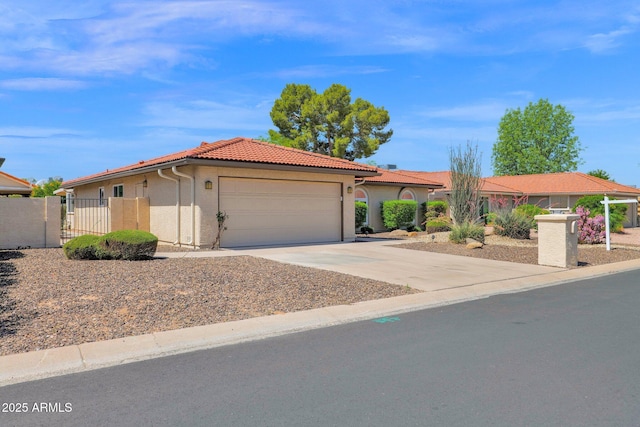 view of front of property with a garage, a tiled roof, driveway, fence, and stucco siding
