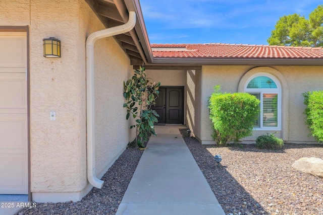 entrance to property featuring stucco siding and a tiled roof
