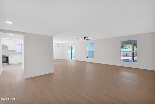 unfurnished living room with light wood-type flooring, a chandelier, baseboards, a ceiling fan, and recessed lighting