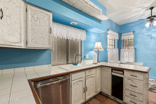 kitchen with kitchen peninsula, tile countertops, sink, and stainless steel dishwasher