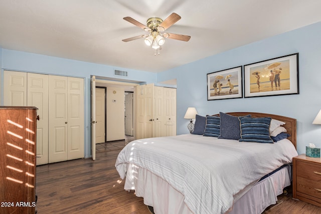 bedroom with dark hardwood / wood-style flooring, two closets, and ceiling fan