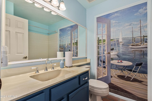 bathroom featuring tiled shower, vanity, and toilet