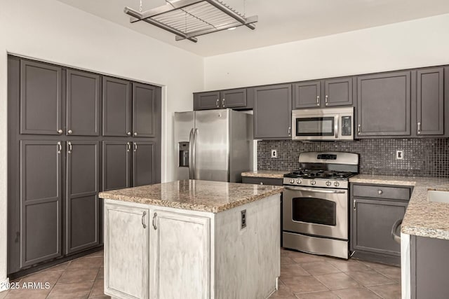 kitchen featuring backsplash, light stone counters, a center island, and appliances with stainless steel finishes