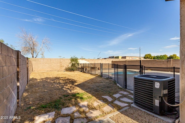 view of yard featuring a fenced in pool and central AC