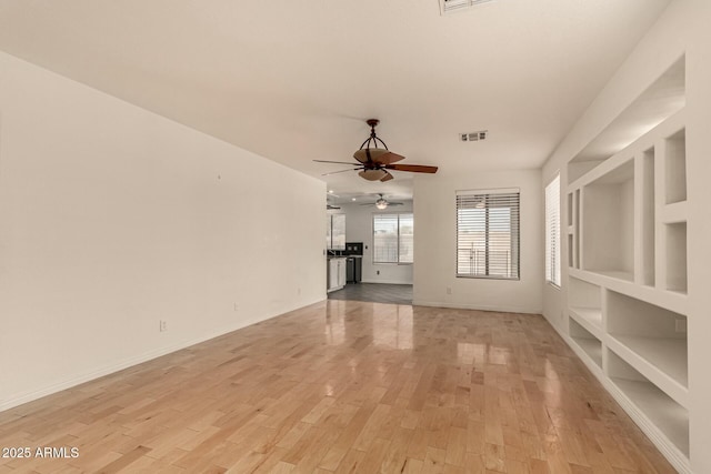 unfurnished living room with light hardwood / wood-style flooring, built in features, and ceiling fan