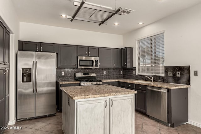 kitchen featuring light stone counters, a kitchen island, light tile patterned flooring, and appliances with stainless steel finishes