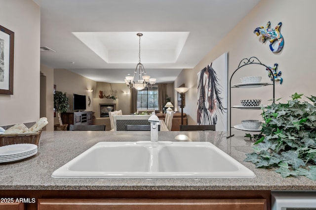 kitchen with a tray ceiling, pendant lighting, visible vents, open floor plan, and a chandelier