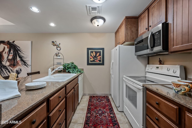 kitchen featuring light tile patterned floors, stone countertops, white appliances, a sink, and visible vents