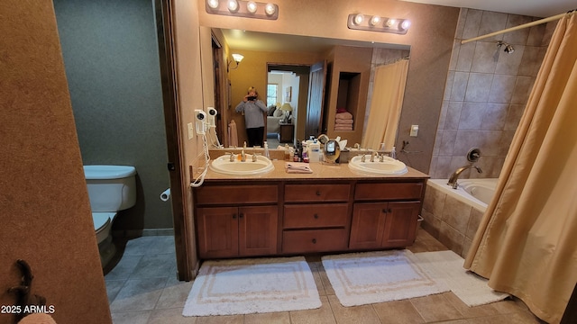 bathroom with toilet, tile patterned flooring, tiled shower / bath, and a sink