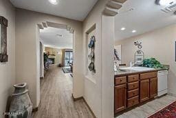 hallway featuring visible vents, a sink, and light wood-style flooring