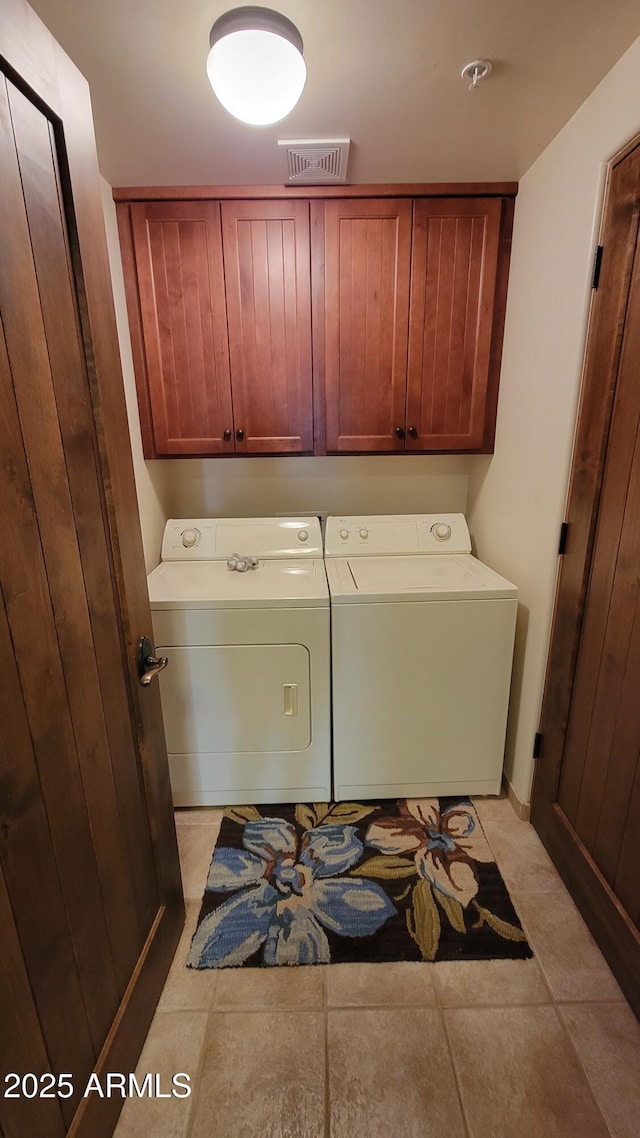 laundry area featuring visible vents, separate washer and dryer, light tile patterned flooring, and cabinet space