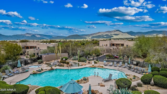 community pool featuring a residential view, a mountain view, a patio, and fence