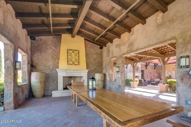 unfurnished dining area with a tile fireplace, beamed ceiling, high vaulted ceiling, and wood ceiling