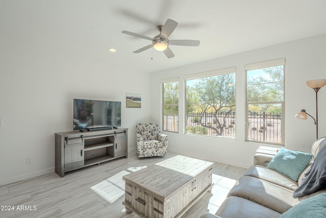 living room with light hardwood / wood-style floors, ceiling fan, and a healthy amount of sunlight