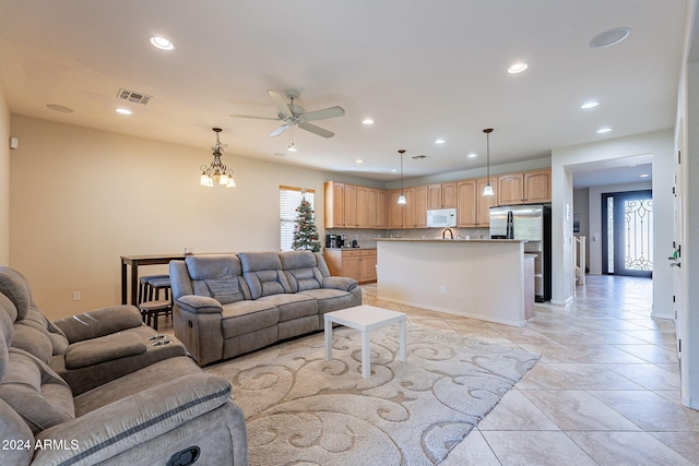 living room with ceiling fan with notable chandelier and sink